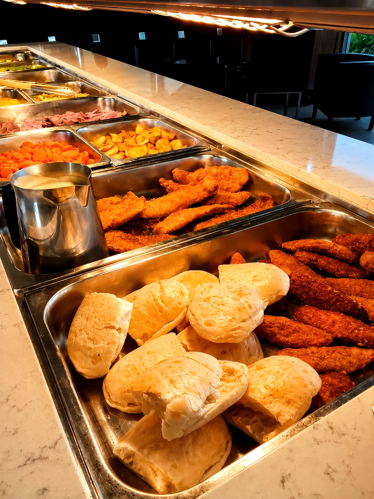 buffet counter with fresh bread rolls, crumbed chicken and roast vegetables