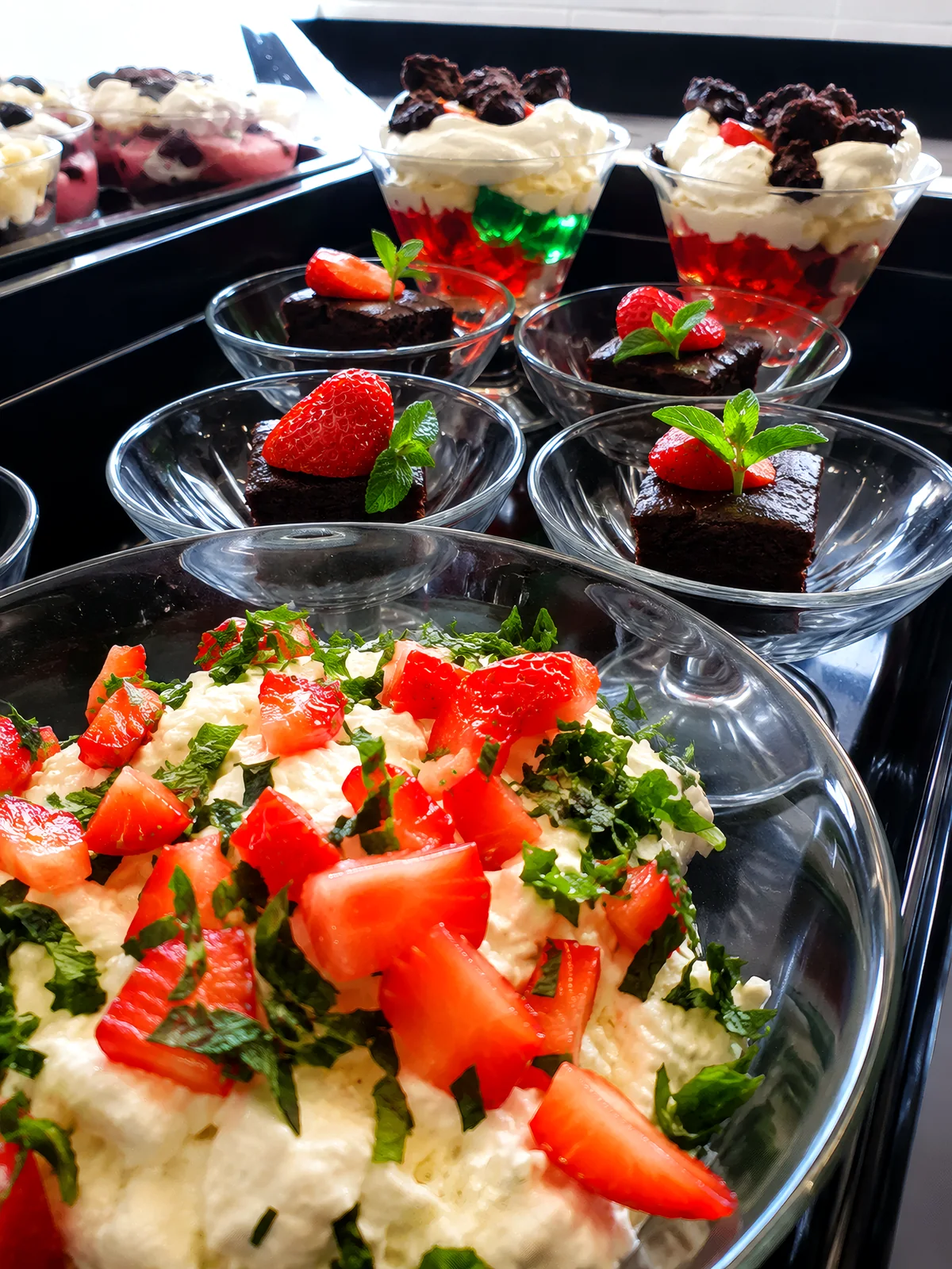 dessert display — chocolate brownies with fresh strawberries and cream, layered trifles